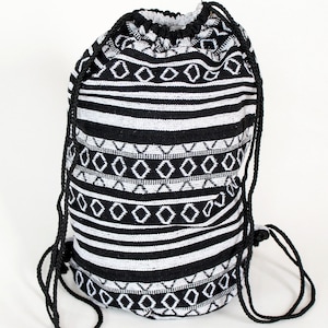 Può includere: Zaino con coulisse bianco e nero con motivo geometrico. La borsa presenta strisce orizzontali e forme a diamante. Il cordino è nero.