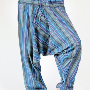 May include: Harem pants with a striped pattern in shades of blue, purple, and green. The pants have a drawstring waist and pockets. The fabric appears lightweight and comfortable.