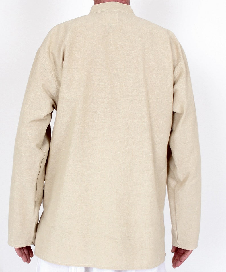 May include: A beige long-sleeved tunic with a mandarin collar. The tunic is made of a textured fabric and has a relaxed fit. The back view shows the full length of the tunic, which extends to the mid-thigh.