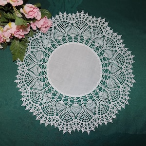 Peut inclure: Une dentelle blanche au crochet avec un motif délicat et complexe. La dentelle est circulaire et a un bord festonné.