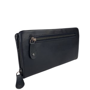 May include: A black leather wallet with a zipper closure. The wallet has a flap with a zippered pocket.