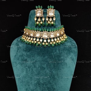 Könnte beinhalten: Eine goldene und grüne Choker-Halskette mit quadratischem Design und smaragdgrünen Perlen. Die Halskette wird mit passenden Ohrringen mit quadratischen Steinen und smaragdgrünen Perlen geliefert.