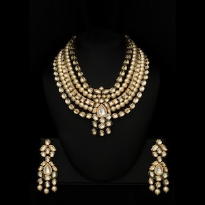 May include: A gold and white layered necklace with pearl accents and a teardrop-shaped pendant. Matching earrings with green accents.