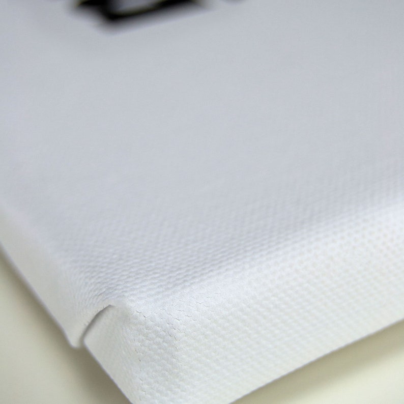 May include: Close-up of the edge of a white canvas, showing the textured weave of the fabric.