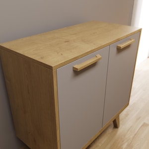 Op de afbeelding: Een kast met twee deuren met een licht houten bovenkant en frame, en grijze deuren. De kast heeft houten handgrepen en staat op korte, schuine poten. Het hout heeft een natuurlijke nerf.