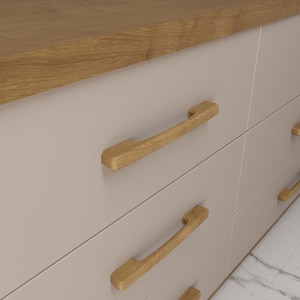 May include: A light beige cabinet with wooden drawer handles. The cabinet has a light brown wooden countertop. The drawer handles are light brown and curved. The cabinet is likely part of a kitchen or bathroom set. The cabinet's dimensions are in centimetres.