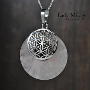 Peut inclure: Un pendentif en argent avec un motif de fleur de vie, posé sur une pierre de quartz rose pâle. Le pendentif est sur une chaîne en argent.