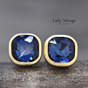 Puede incluir: Un par de pendientes de oro con piedras preciosas cuadradas azules. Los pendientes están engastados en un engaste de bisel de oro.