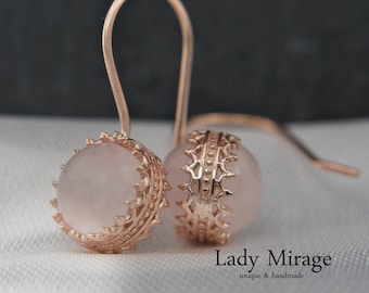 May include: Rose quartz earrings with a delicate, ornate gold setting. The earrings are dangle style with a hook closure.