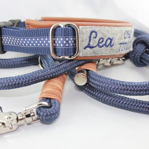 May include: A blue dog collar and leash set. The collar features a blue and white polka dot pattern and the name "Lea" embroidered in blue. The leash is a matching blue rope with a silver clasp and hardware. The collar has brown leather accents.