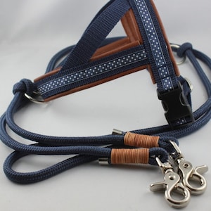 May include: A navy blue dog harness and leash set. The harness features brown leather and a white polka dot pattern on the navy blue straps. The leash is a matching navy blue rope with silver-colored clasps.