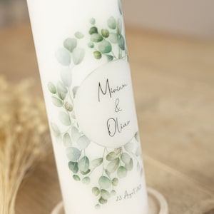 May include: White wedding candle with a eucalyptus leaf design and the names Miriam & Oliver and the date 23 August 2023.