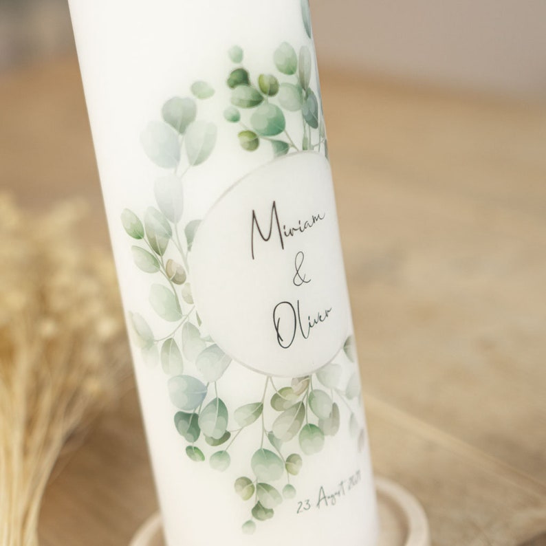 May include: White wedding candle with a eucalyptus leaf design and the names Miriam & Oliver and the date 23 August 2023.