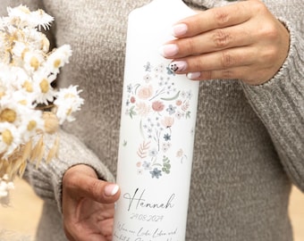 May include: White baptism candle with a floral cross design and the name "Hannah" and the date "24.08.2024" printed on it. The text "Wenn aus Liebe Leben wird,  hat der Glück einen Namen" is also printed on the candle.