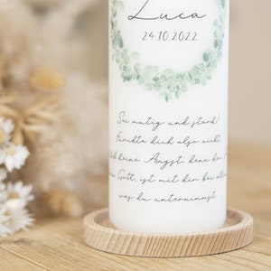 May include: White candle with a green leafy wreath design and the text "Luca 24.10.2022". The candle also has the text "Sei mutig und stark! Furchte dich also nicht. Hab keine Angst; denn der Herr Gott, ist mit dir bei allem was du unternimmst."