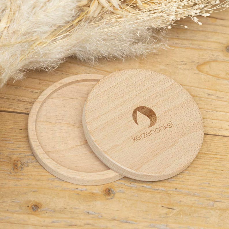 Puede incluir: Dos posavasos redondos de madera con un acabado de madera natural. El posavasos superior tiene el texto "kerzenonkel" y un dise&ntilde;o de llama estilizado.