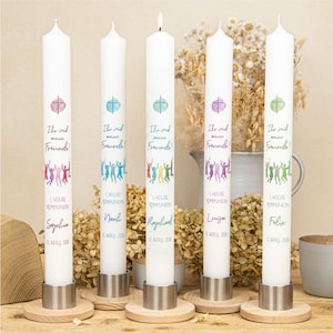 May include: Five white pillar candles with colorful designs and text. Each candle has a unique name and date. The candles are in metal holders on wooden bases. The text on the candles reads "Ihr seid meine Freunde!" and "1. Heilige Kommunion".