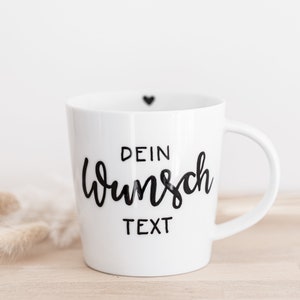 Könnte beinhalten: Weiße Keramiktasse mit einem schwarzen Herz oben und dem Text "DEIN WUNSCH TEXT" in schwarzer Schrift.