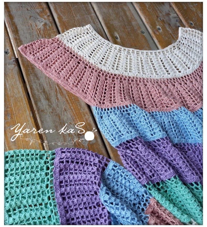 Pode incluir: Top de croch&ecirc; multicolorido feito &agrave; m&atilde;o, com decote franzido. O top apresenta um design de blocos de cores com sec&ccedil;&otilde;es brancas, rosa, azul, roxo e verde. O texto "Yaren ka S" &eacute; vis&iacute;vel.