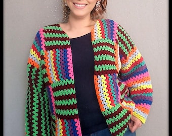 Puede incluir: Chaqueta de crochet abierta, colorida y con diseño de patchwork. La chaqueta presenta una vibrante mezcla de colores arcoíris, incluyendo verde, naranja, rosa y azul, con un borde marrón oscuro. Las mangas son largas y el estilo es casual.