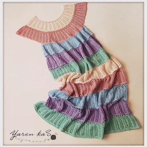 Pode incluir: Um vestido de croch&ecirc; feito &agrave; m&atilde;o, multicolorido, em tons pastel. O vestido apresenta um decote redondo e uma saia com babados em camadas. As cores incluem rosa, azul claro, roxo, verde e creme.