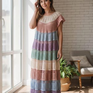Pode incluir: Um vestido longo de croch&ecirc; multicolorido. O vestido apresenta listras horizontais em tons pastel de rosa, azul, verde e roxo. A parte superior &eacute; de cor s&oacute;lida, transformando-se na saia listrada. Possui mangas curtas e decote redondo.