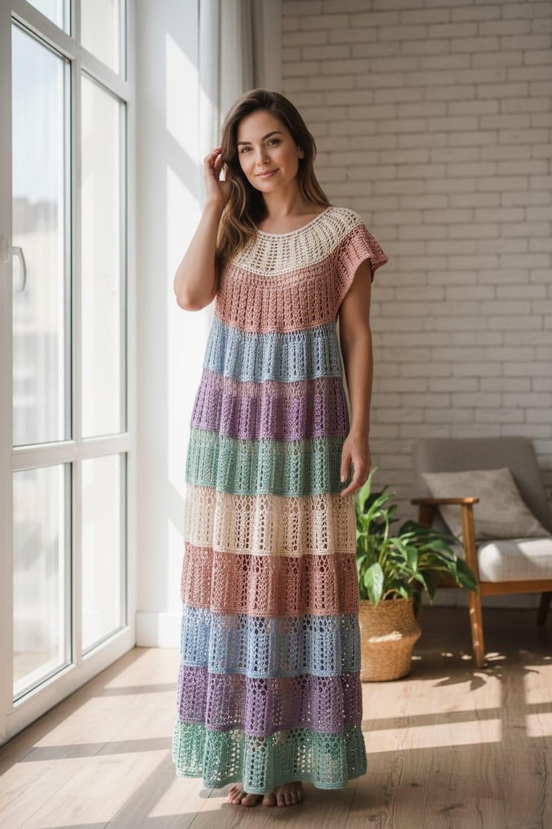 Pode incluir: Um vestido longo de croch&ecirc; multicolorido. O vestido apresenta listras horizontais em tons pastel de rosa, azul, verde e roxo. A parte superior &eacute; de cor s&oacute;lida, transformando-se na saia listrada. Possui mangas curtas e decote redondo.