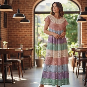 Pode incluir: Um vestido longo de croch&ecirc; multicolorido. O vestido apresenta listras horizontais em tons pastel de creme, rosa, azul, verde e roxo. Possui mangas curtas e decote redondo. O vestido &eacute; feito de um tecido leve e de trama aberta.
