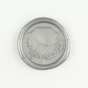 May include: A silver wax seal with a shield and wreath design.
