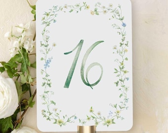 Puede incluir: Tarjeta blanca con un borde floral verde y el número 16 en acuarela verde. La tarjeta está unida a un soporte de metal dorado.
