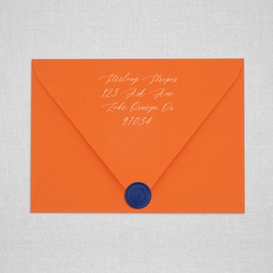 May include: An orange envelope with a white address label that reads "Sterling Stripes, 123 Ash Ave, Lake Oswego, OR 97034". The envelope has a blue wax seal.