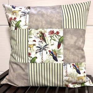 Könnte beinhalten: Ein quadratisches Kissen mit Patchwork-Design aus verschiedenen Stoffen. Das Kissen besteht aus sechs verschiedenen Quadraten, jedes mit einem anderen Muster. Die Muster umfassen Streifen, eine einfarbige Farbe und einen Blumendruck mit Vögeln und Tigern. Das Kissen ist in neutralen Beige- und Grüntönen gehalten.