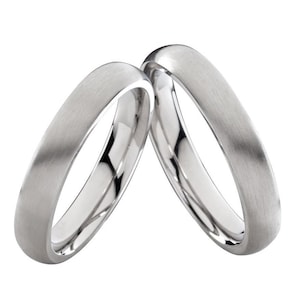 Könnte beinhalten: Zwei silberne Eheringe mit gebürsteter Oberfläche.