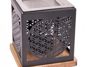 May include: A black metal cube-shaped incense burner with a stainless steel top and a wooden base. The sides feature intricate cut-out patterns. The burner is designed for incense sticks or cones, creating a decorative and functional item.