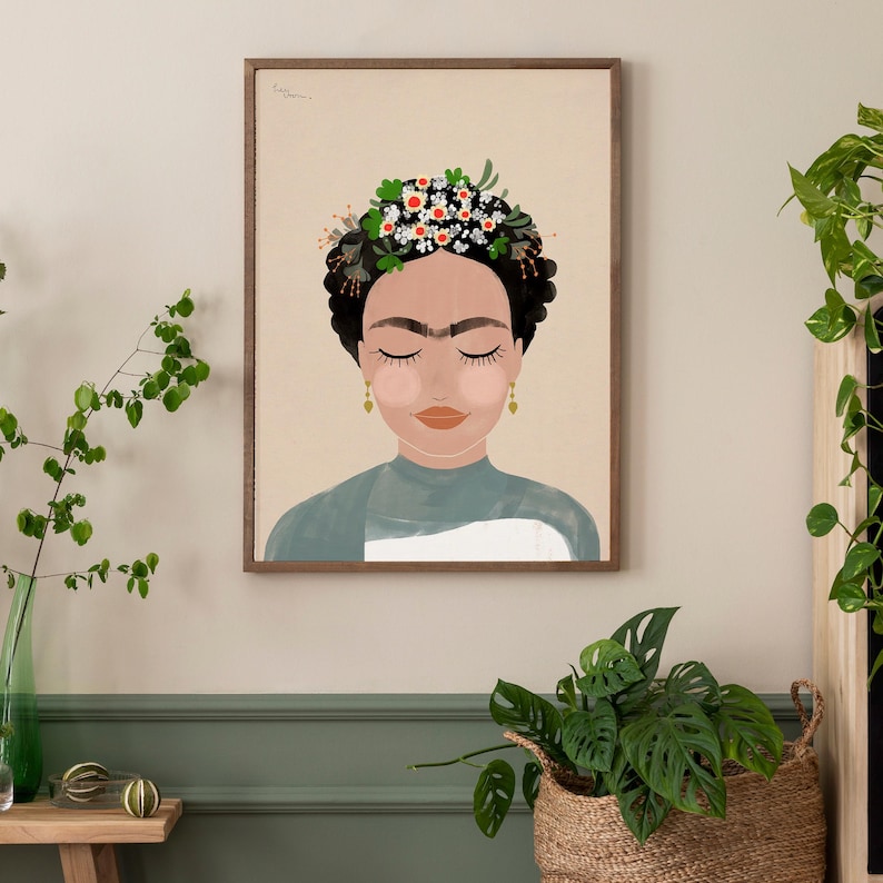 May include: A framed illustration of a woman with closed eyes wearing a flower crown. The woman has dark hair and brown skin. The background is a light beige color.