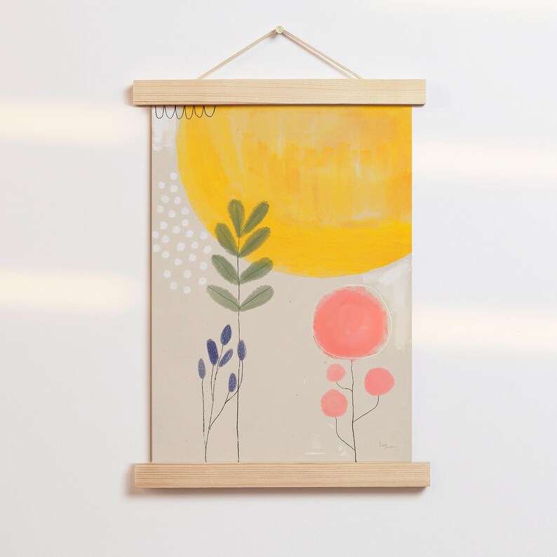 Może przedstawiać: Minimalistyczny wydruk artystyczny z ż&oacute;łtym słońcem, zielonymi liśćmi i r&oacute;żowymi kwiatami na beżowym tle. Wydruk jest oprawiony w drewnianą ramę i wisi na białej ścianie.