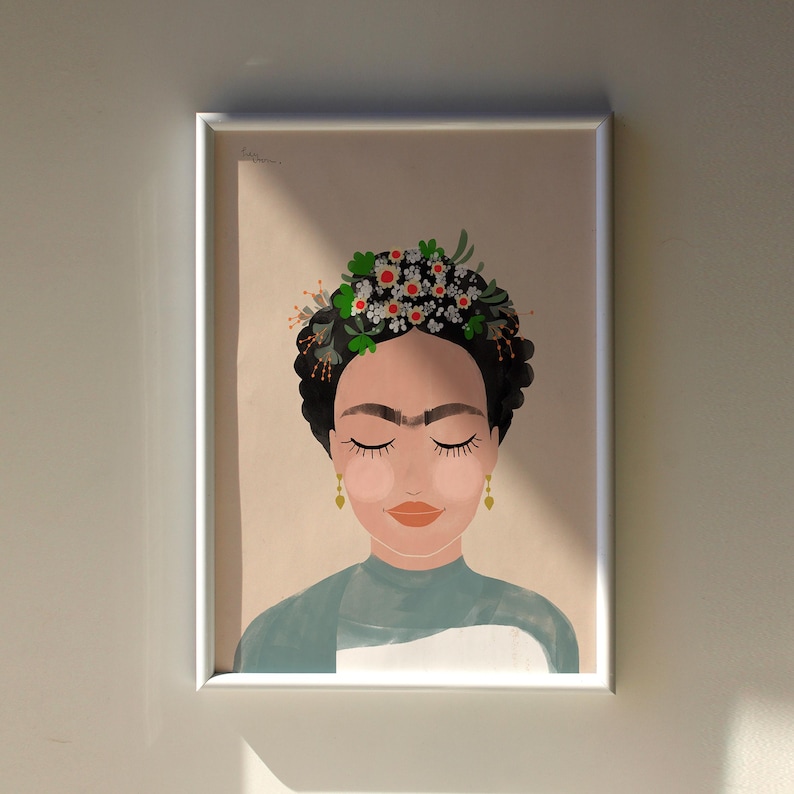 May include: A framed illustration of a woman with dark hair and a flower crown. She is wearing a blue shirt and has her eyes closed. The background is a light peach color.