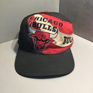 May include: A black, red, and white baseball cap with the Chicago Bulls logo and the words "Chicago Bulls" embroidered on the front.