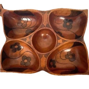 May include: Wooden serving tray with five compartments. The tray is stained a warm brown and features a floral design in each of the four outer compartments. The center compartment is a round bowl. The tray is ideal for serving snacks or appetizers.