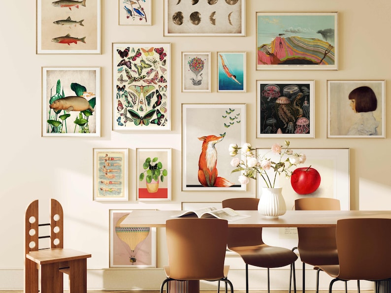 May include: A dining room with a white wall featuring a gallery wall of framed prints. The prints include images of fish, butterflies, a fox, a jellyfish, and a red apple. There is a wooden chair and a table with four chairs.