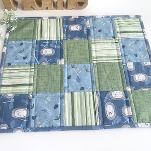 Peut inclure: Un set de table patchwork bleu et vert avec différents motifs, notamment des rayures, des libellules et des hérissons.