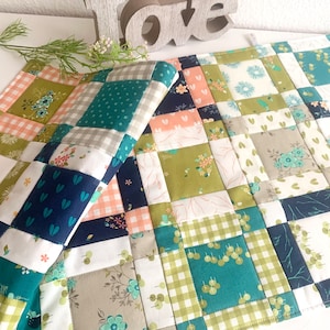 Könnte beinhalten: Zwei Patchwork-Platzsets in verschiedenen floralen und geometrischen Mustern, darunter grüne, blaue, weiße und rosa Stoffe. Die Platzsets sind aus Baumwollstoff gefertigt und perfekt, um Ihrem Esstisch einen Hauch von handgemachtem Charme zu verleihen.