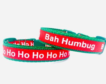 May include: Two Christmas-themed dog collars. The collars are red with white text that reads "Ho Ho Ho Ho" and "Bah Humbug". The edges of the collars are green.