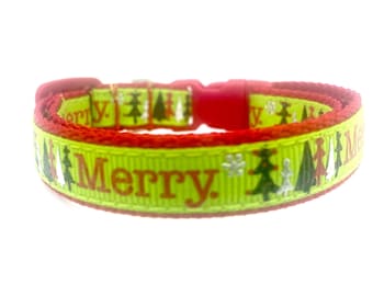 May include: A festive pet collar with a bright green base and red trim. The collar features the word "Merry" in red, along with Christmas tree and snowflake graphics. The collar has a red plastic buckle.