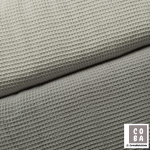 Könnte beinhalten: Zwei Waffelpiqué-Stoffmuster, eines weiß und eines grau. Der Stoff ist strukturiert und hat ein Waffelmuster.
