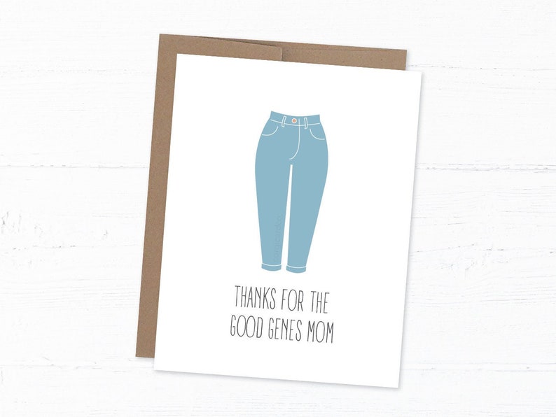 White card with illustration of mom jeans with "thanks for the good genes mom" written below. With kraft envelope behind and white wood background.