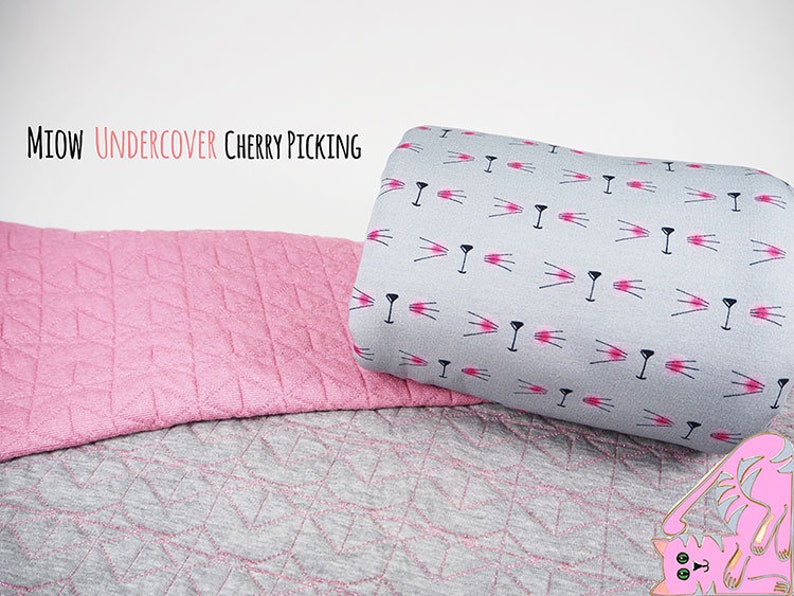 May include: Two pieces of fabric, one pink with a diamond pattern and one gray with a repeating pattern of pink cat faces. The text "MIOW UNDERCOVER CHERRY PICKING" is at the top of the image.