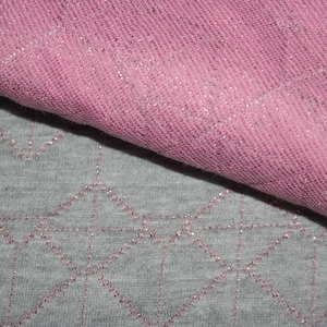 May include: Two pieces of fabric, one pink and one gray, with a sparkly texture. The pink fabric is folded over the gray fabric.