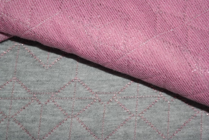 May include: Two pieces of fabric, one pink and one gray, with a sparkly texture. The pink fabric is folded over the gray fabric.
