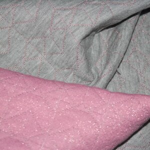 May include: Two pieces of fabric, one gray and one pink, with a diamond pattern. The fabric is soft and textured.